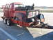1952 Ford Pickup - A vintage red pickup truck, loaded with various parts, is being transported on a trailer down a highway.
