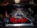 1984 Ford Bronco - Engine bay view of a V8 engine chrome valve covers and a red engine block, likely undergoing restoration or modification.