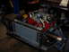 1984 Ford Bronco - Close-up view of a vehicle's engine and radiator assembly, a red engine block and chrome valve covers.