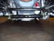 1984 Ford Bronco - A close-up view of a vehicle's front suspension system, showing mechanical components and the floor below.
