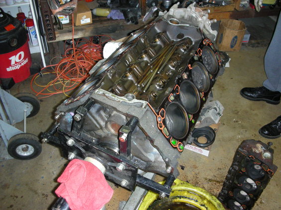 Engine block on a stand, with parts and tools in the background