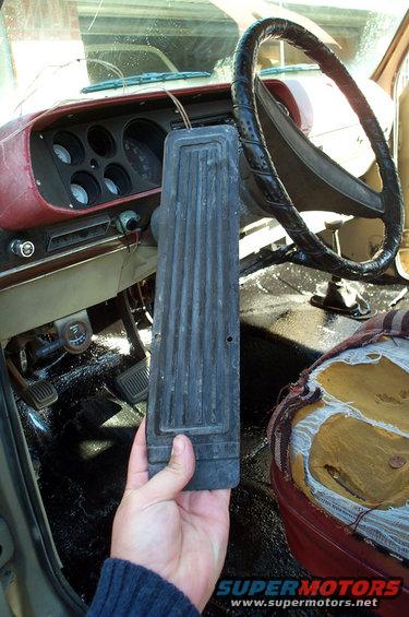 Hand holding a black ribbed pedal pad in a truck cab. Dashboard and steering wheel visible