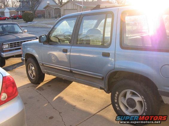 Light blue SUV parked on a driveway, another SUV and part of a car visible