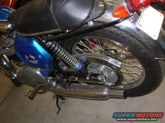 Blue motorcycle side panel with flag decals and chrome exhaust