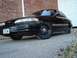 1992 Ford Crown Victoria - This black sedan is parked on a gravel surface with a brick wall and a large garage door in the background.