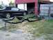 2004 Ford Mustang - A black convertible sits beside a freshly painted car frame, with another vehicle partially visible inside a barn.