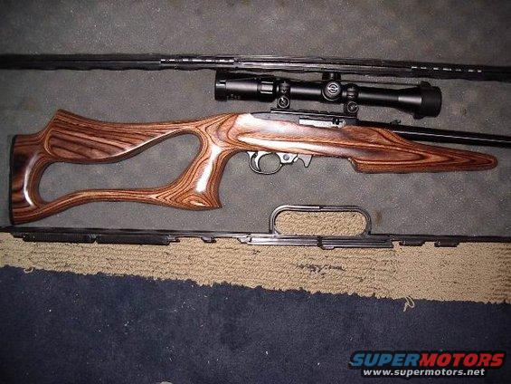 Rifle with wooden stock and scope, lying on a mat