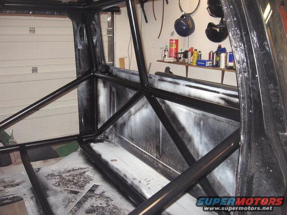 Interior of a truck with a black roll cage installed. The bed and cab area are visible