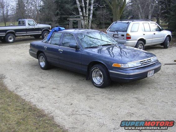 Blue 1996 Ford Crown Victoria sedan with chrome wheels parked outside