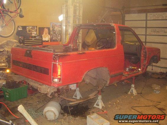 Red Chevrolet S-10 Blazer on jack stands, missing doors and roof, in a garage