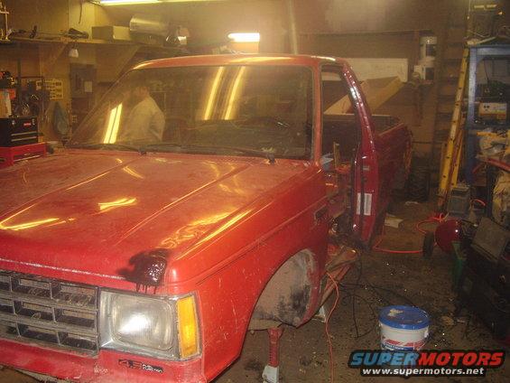 red pickup truck with door open, missing fender, in garage
