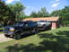 1995 Ford C-350 (Centurion Conversions) - A green Ford Bronco SUV is parked on a driveway, towing a white pickup truck on a trailer.