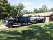1995 Ford C-350 (Centurion Conversions) - Ford SUV towing a Dodge pickup truck on a trailer in front of a garage.