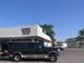 1995 Ford C-350 (Centurion Conversions) - A dark green SUV with tan trim is parked in front of Dorsey Trailer Sales under a clear blue sky.