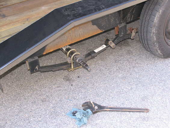 Trailer axle with leaf springs and a large adjustable wrench on the ground