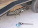 1995 Ford C-350 (Centurion Conversions) - Close-up of a trailer's suspension system, showing leaf springs and a spindle, with a wrench nearby.