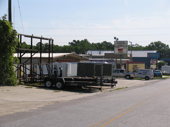 Silver pickup truck parked in front of buildings with trailers