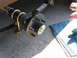 1995 Ford C-350 (Centurion Conversions) - Close-up of a trailer axle hub assembly being greased, with a leaf spring and U-bolts visible.