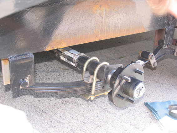 Trailer axle with leaf spring suspension and hub assembly. Visible part of black frame above
