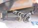1995 Ford C-350 (Centurion Conversions) - Close-up view of a trailer's axle and suspension system, showing the leaf springs and hub.