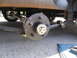 1995 Ford C-350 (Centurion Conversions) - Close-up view of a trailer's axle, leaf springs, and wheel hub assembly.