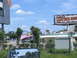 1995 Ford C-350 (Centurion Conversions) - A view of commercial buildings along a road on a sunny day with a blue sky and scattered clouds.