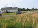 1995 Ford C-350 (Centurion Conversions) - A blue pickup truck drives down a road past a house and tall grass.