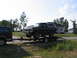 1995 Ford C-350 (Centurion Conversions) - A dark blue Ford Bronco is loaded onto a trailer, with another dark vehicle visible in the foreground.