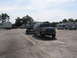 1995 Ford C-350 (Centurion Conversions) - A dark green Ford Bronco is seen towing a trailer with a pickup truck. Other vehicles are parked in the lot.