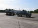 1995 Ford C-350 (Centurion Conversions) - A dark green Ford Bronco is transported on a trailer pulled by a Ford F-Series truck.