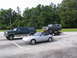 1995 Ford C-350 (Centurion Conversions) - Three vehicles are parked in a lot: a Ford Bronco on a trailer, a Ford Econoline van, and a Mazda Miata convertible.
