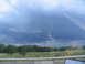 1995 Ford C-350 (Centurion Conversions) - Stormy weather approaches over a rural landscape, seen through a vehicle's window.