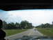 1995 Ford C-350 (Centurion Conversions) - A view from inside a vehicle shows a two-lane road with a white pickup truck and other cars under a cloudy sky.
