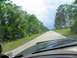1995 Ford C-350 (Centurion Conversions) - Driving down a country road with a cloudy sky overhead and trees lining the asphalt.