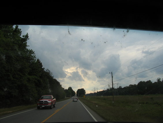 Red pickup truck driving on a highway under a cloudy sky