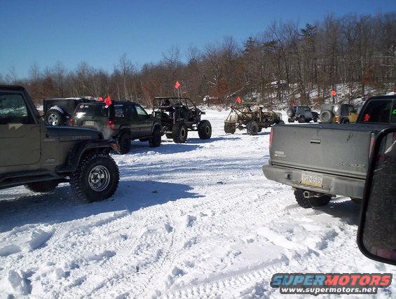 Several off-road vehicles parked in the snow on a sunny day