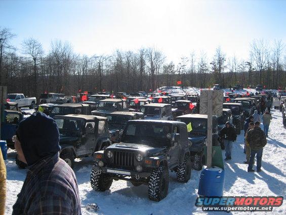 Front view of a 2002 Jeep Wrangler with large tires in a snowy lot full of other Jeeps