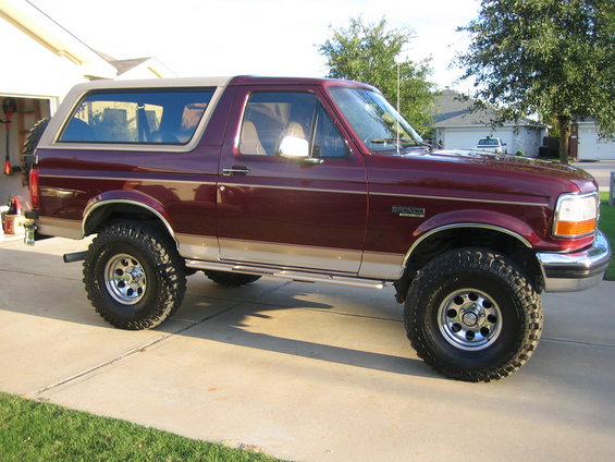 Maroon 1996 Ford Bronco side view with tan top and off-road tires
