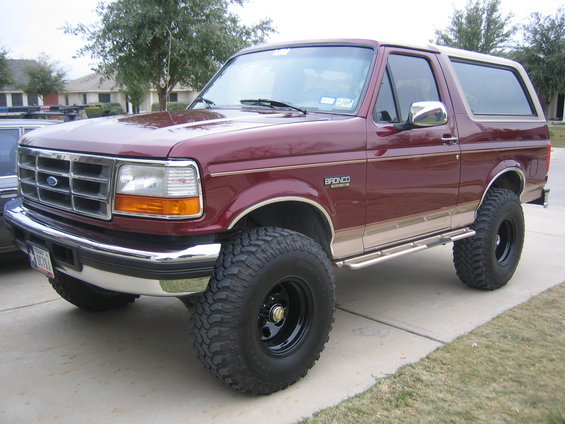 Maroon Ford Bronco with tan trim and lifted suspension, parked on a driveway