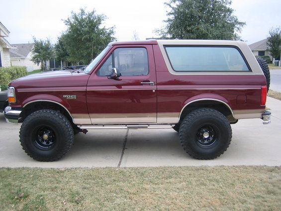 Maroon and tan 1996 Ford Bronco side view with lifted suspension and off-road tires