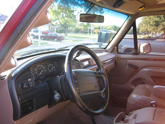 Interior of a red SUV, tan leather seats, dashboard with gauges, steering wheel, and aftermarket gauges on the A-pillar