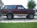 1996 Ford Bronco - A maroon and tan 1996 Ford Bronco SUV is shown from the side, parked on a concrete driveway.