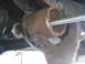 1996 Ford Bronco - Close-up of a gloved hand manipulating a rusted metal pipe with a threaded rod inserted, likely during a repair or modification.