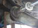 1996 Ford Bronco - A close-up view of a vehicle's suspension system, showing a bolt being installed into a rusty component.