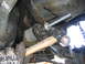 1996 Ford Bronco - Close-up of a mechanic using a hammer and bolt to install a suspension bushing on a vehicle.