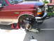 1996 Ford Bronco - A red Ford Bronco with tan trim is elevated on jack stands, undergoing suspension work.