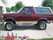 1996 Ford Bronco - A maroon 1996 Ford Bronco with a tan top is parked on jack stands, suggesting a lift installation is in progress.