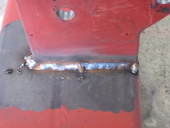 Red metal bracket with a visible weld seam and a threaded hole