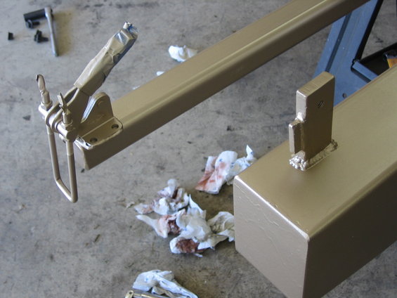 Trailer hitch receiver and mounting bracket, painted tan, with used rags on concrete floor