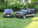1995 Ford C-350 (Centurion Conversions) - Two Ford SUVs, a Bronco and a Centurion Conversion, are parked on a grassy lawn with trees in the background.